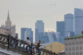 People walk along at the bridge, with the Moscow International Business Centre also known as "Moskva-City" seen in the background in Moscow, Russia