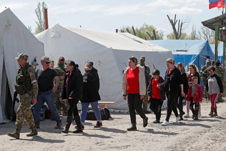 Civis que deixaram a área perto da usina de aço Azovstal em Mariupol caminham em um centro de acomodação temporária