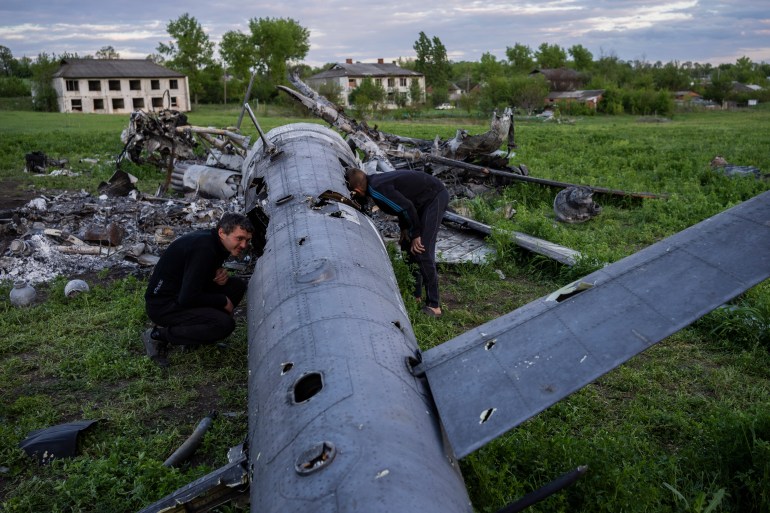 Oleksiy Polyakov, right, and Roman Voitko, check the remains of a destroyed Russian helicopter in a field in the village of Malaya Rohan, Kharkiv region
