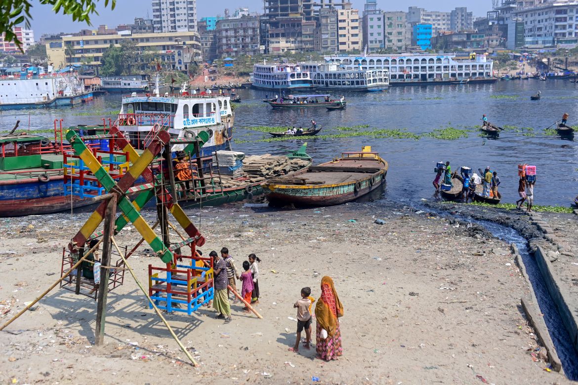 In this picture taken on March 13, 2022, industrial effluents enter the waters of the Buriganga River as children wait to board a Ferris wheel ride along the river bank in Karanigonj, on the outskirts of Dhaka
