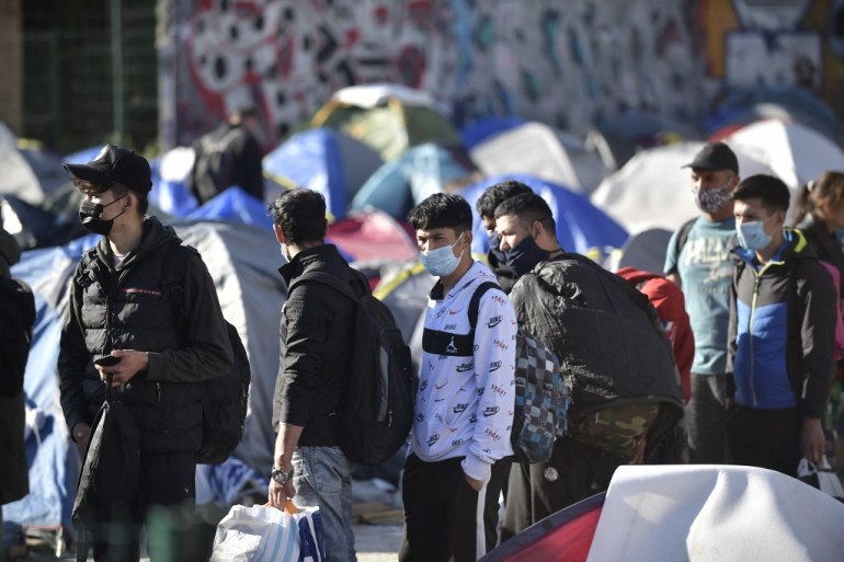 Asylum seekers line up with their belongings next to tents during the evacuation of a camp of migrants, mainly from Afghanistan, by police forces in Pantin, northeastern suburbs of Paris