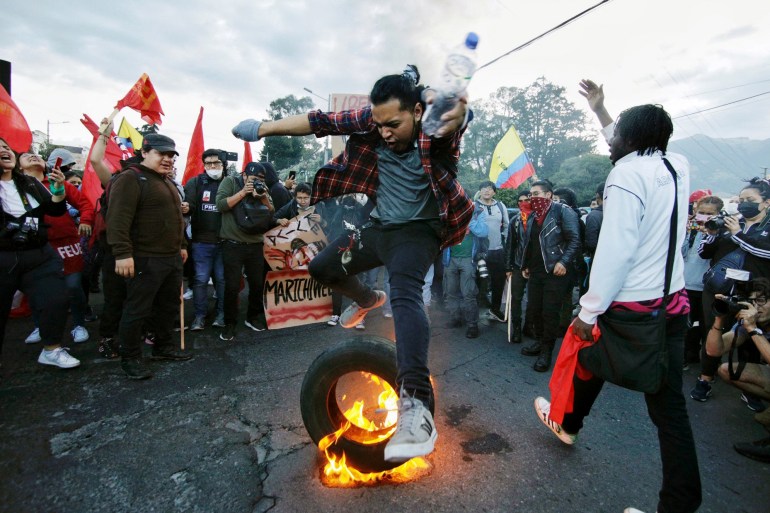 A university student leaps over a burning tyre during a demonstration