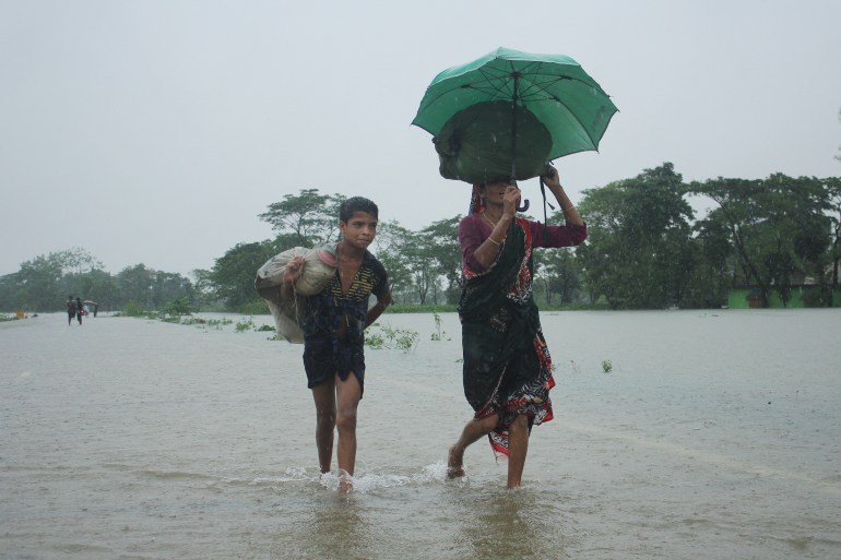 People wade along a road in a flooded area