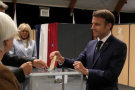 France's President Emmanuel Macron casts his ballot next to his wife Brigitte Macron during the second stage of French parliamentary elections at a polling station in Le Touquet, northern France