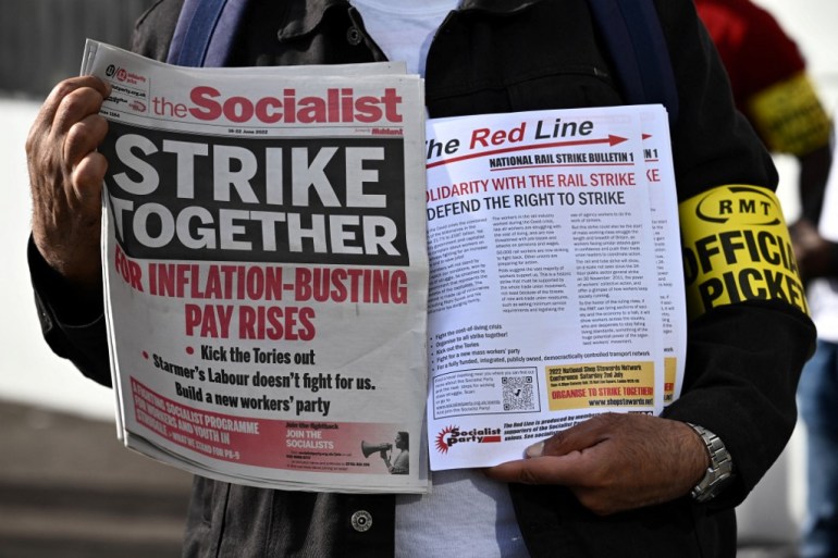 Pamphlets and newspapers are distributed at a picket line outside Waterloo Station in London on June 21, 2022 as the biggest rail strike in over 30 years hits the UK. - Rush-hour commuters in the UK faced chaos as railway workers began the network's biggest strike action in more than three decades, with a cost-of-living crisis threatening wider industrial action. (Photo by Ben Stansall / AFP)