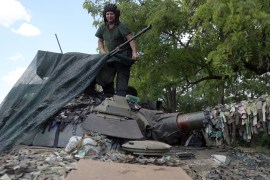 A Ukrainian serviceman covers the turret of an tank in the eastern Ukrainian region