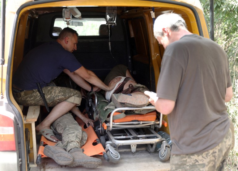 Украинские военнослужащие оказывают помощь раненому однополчанину во время медицинской эвакуации.