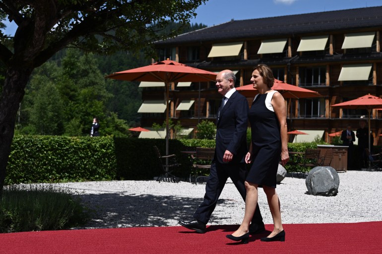 Germany's Chancellor Olaf Scholz and his wife Britta Ernst walk on a red carpet.