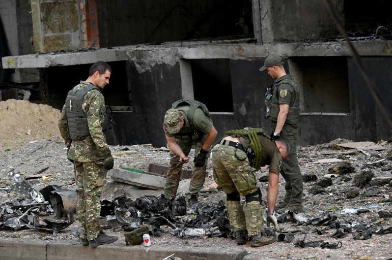 Ukrainian experts work outside a damaged residential building hit by Russian missiles in Kyiv on June 26, 2022