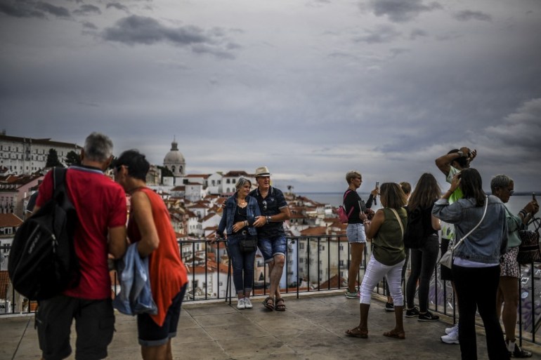 Tourists pose for pictures at Portas do Sol viewpoint in Alfama, Lisbon