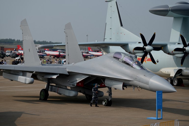 A military personnel walks past Shenyang Aircraft Corporation's J-16 multirole strike fighter for the People's Liberation Army Air Force (PLAAF) at the 13th China International Aviation and Aerospace Exhibition in Zhuhai in southern China's Guangdong province