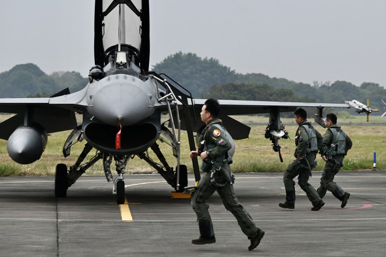 Taiwanese air force pilots run pass an armed US-made F-16V fighter at an air force base in Chiayi, southern Taiwan in January 2022 [Sam Yeh/AFP]