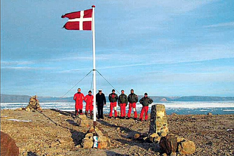 A group of Danish soldiers and the Danish flag stand on the Hans Island between Greenland and Canada