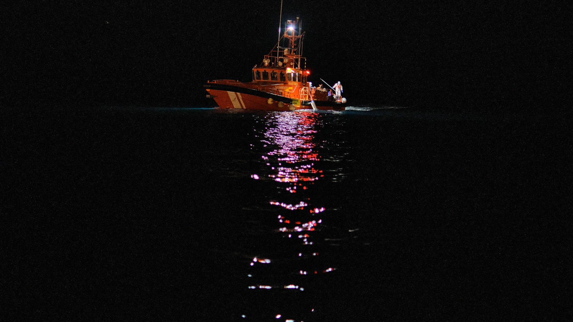 A photo of a Spanish search and rescue vessel in the dark.