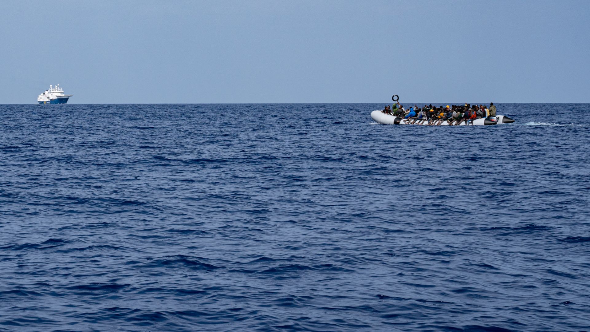 An inflatable boat with over 100 people onboard floats in the Med sea