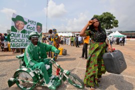 A disabled man rides outside a fuel station where people queue to buy kerosene, in Nigeria's capital Abuja
