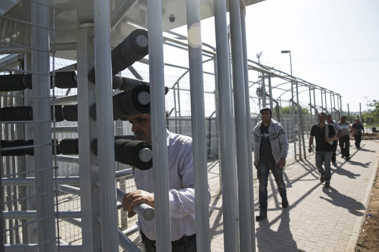 Palestinian labourers with permits to work in Israel walk through a turnstile as they return to the West Bank at Israel's Eyal checkpoint.