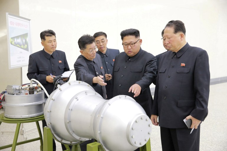 Kim Jong Un, standing in front of what appears to be some sort of weapons mock-up with his advisers in 2017.