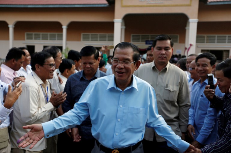 Hun Sen in a blue shirt greets commune leaders at a meeting in 2018 