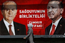 Woman walks past a billboard featuring Turkish President Erdogan and MHP leader Bahceli
