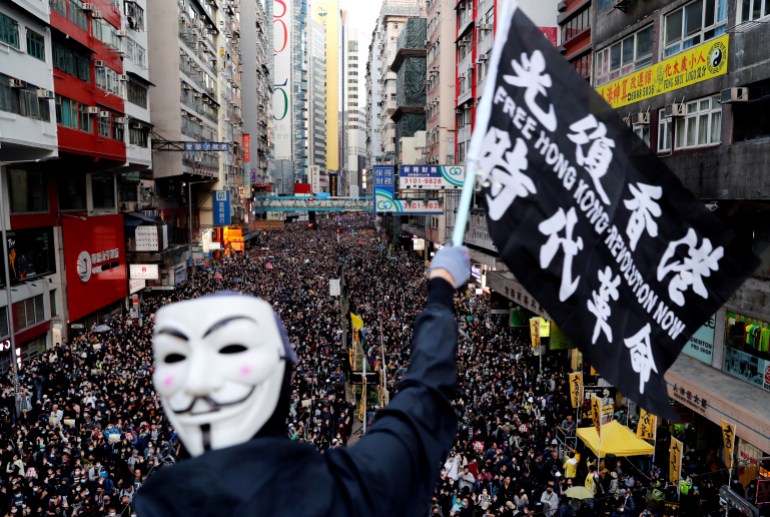 Guy Fawkes maskesi takan bir protestocu, 8 Aralık 2019'da Çin'in Hong Kong kentinde Sivil İnsan Hakları Cephesi tarafından düzenlenen İnsan Hakları Günü yürüyüşü sırasında bayrak sallıyor.