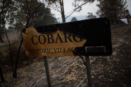 A yellow sign welcoming people to Cobargo is burned black from the fires in 2019/2020
