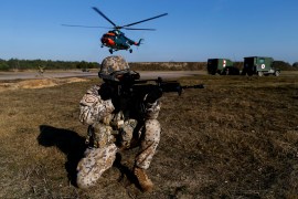 A Latvian army soldier holds a weapon as a helicopter lands during a NATO military drill in 2020 [File: Ints Kalnins/Reuters]