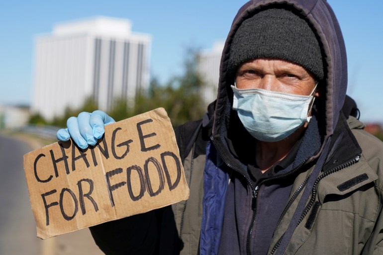 Man carrying cardboard sign "Change for Food"