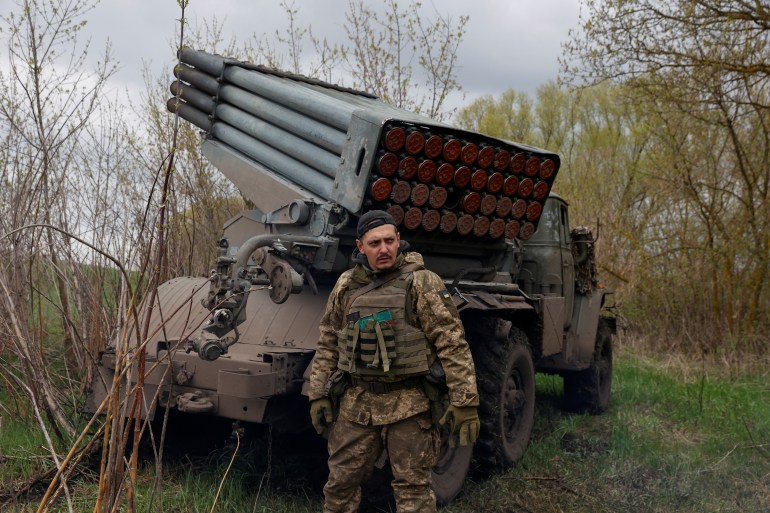A Ukrainian serviceman stands next to a BM-21 Grad multiple rocket launch system,
