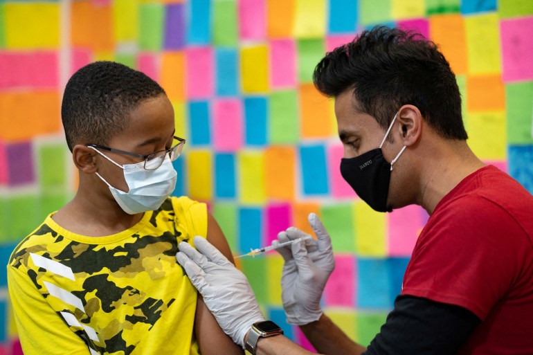 Dr. Mayank Amin administers a Pfizer-BioNTech coronavirus disease (COVID-19) booster vaccine to 10-year-old Ernest "EJ" Jones at Skippack Pharmacy in Schwenksville, Pennsylvania,