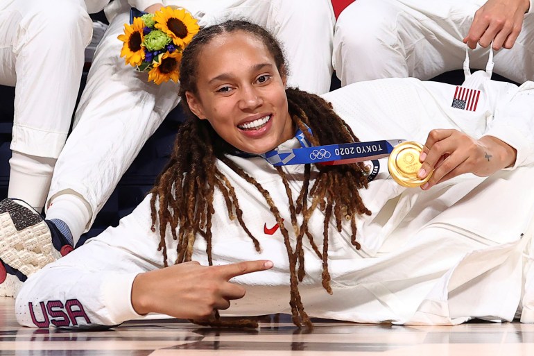 Brittney Griner smiles and points at her Olympic gold medal for basketball at the 2020 Tokyo Olympics