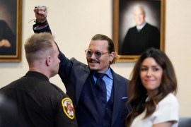 Johnny Depp, with his lawyer to his left and a court security guard to his right, waves to people in court during his defamation trial against ex-wife Amber Heard
