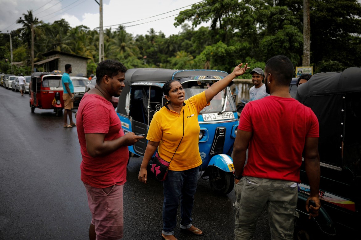 Lasanda Deepthi, 43, an auto-rickshaw driver for local ride hailing app PickMe, talks to other drivers as they wait in a queue to buy petrol at a fuel station in Gonapola town, on the outskirts of Colombo