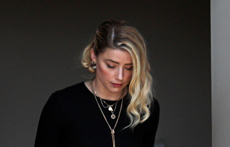 A solemn Amber Heard, in black and wearing multiple necklaces, leaves court after the decision