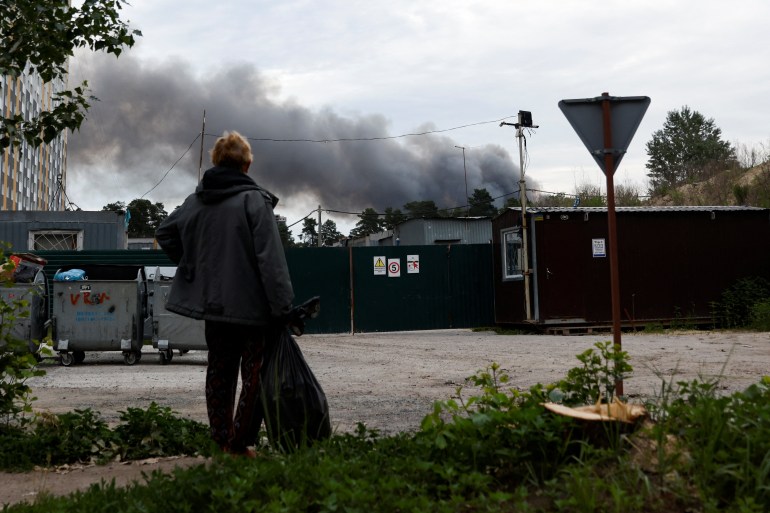 A man looks at the smoke after explosions were heard as Russia's attacks on Ukraine continues.