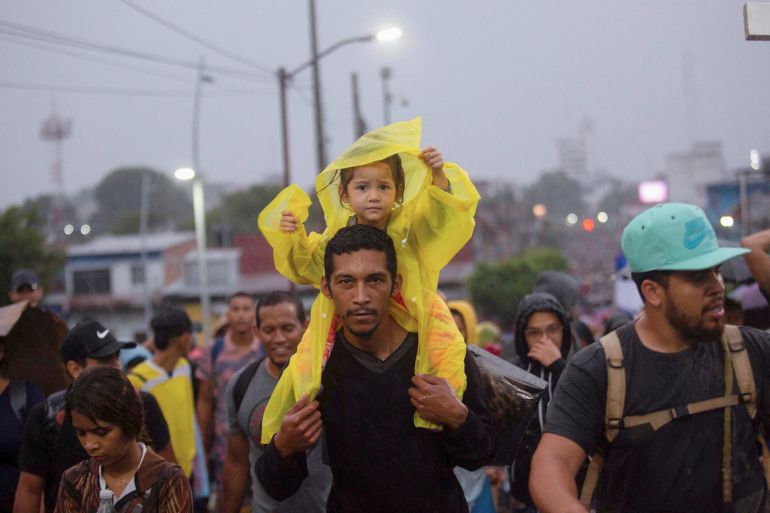 A child sits on a man's shoulders as a caravan departs Mexico for the US border