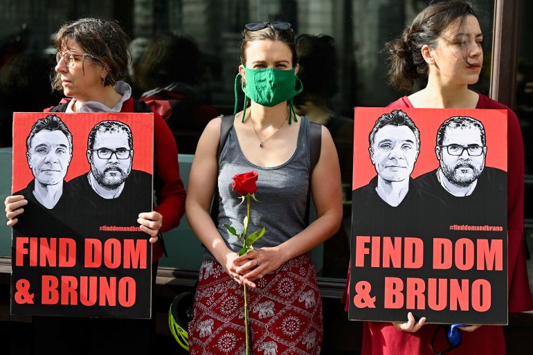 Demonstrators hold signs and roses to demand action to find a missing British journalist and Indigenous expert in Brazil