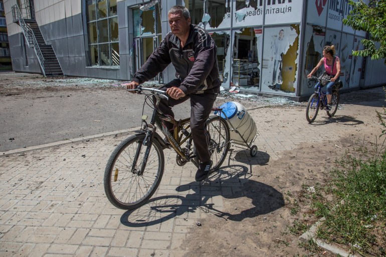 A local man rides a bicycle with an attached water container, as Russia's attack on Ukraine continues, in the town of Lysychansk, Luhansk region, Ukraine June 10, 2022. Picture taken June 10, 2022. REUTERS/Oleksandr Ratushniak
