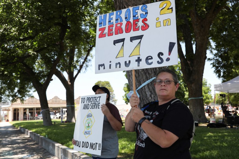 Protesters hold placards criticising police for their slow response to the attack on the Robb Elementary School One says 'Heroes 2 Zeroes in 77 minutes' referring to the amount of time officers waited to act.