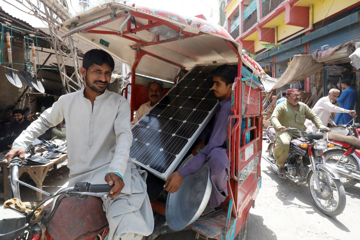 People in a rickshaw carry a solar panel, during a heatwave, in Jacobabad