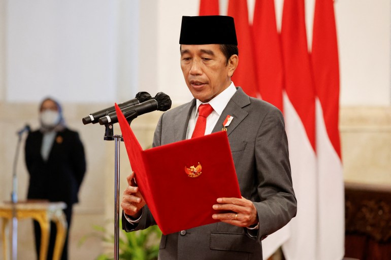 El presidente de Indonesia, Joko Widodo, lee una proclama frente a una fila de banderas de Indonesia.