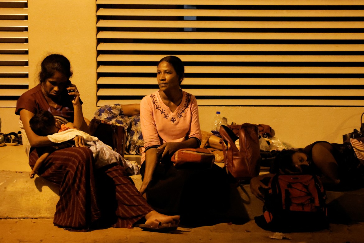 A woman with a baby spend the night with others outside the Sri Lanka's Immigration and Emigration Department