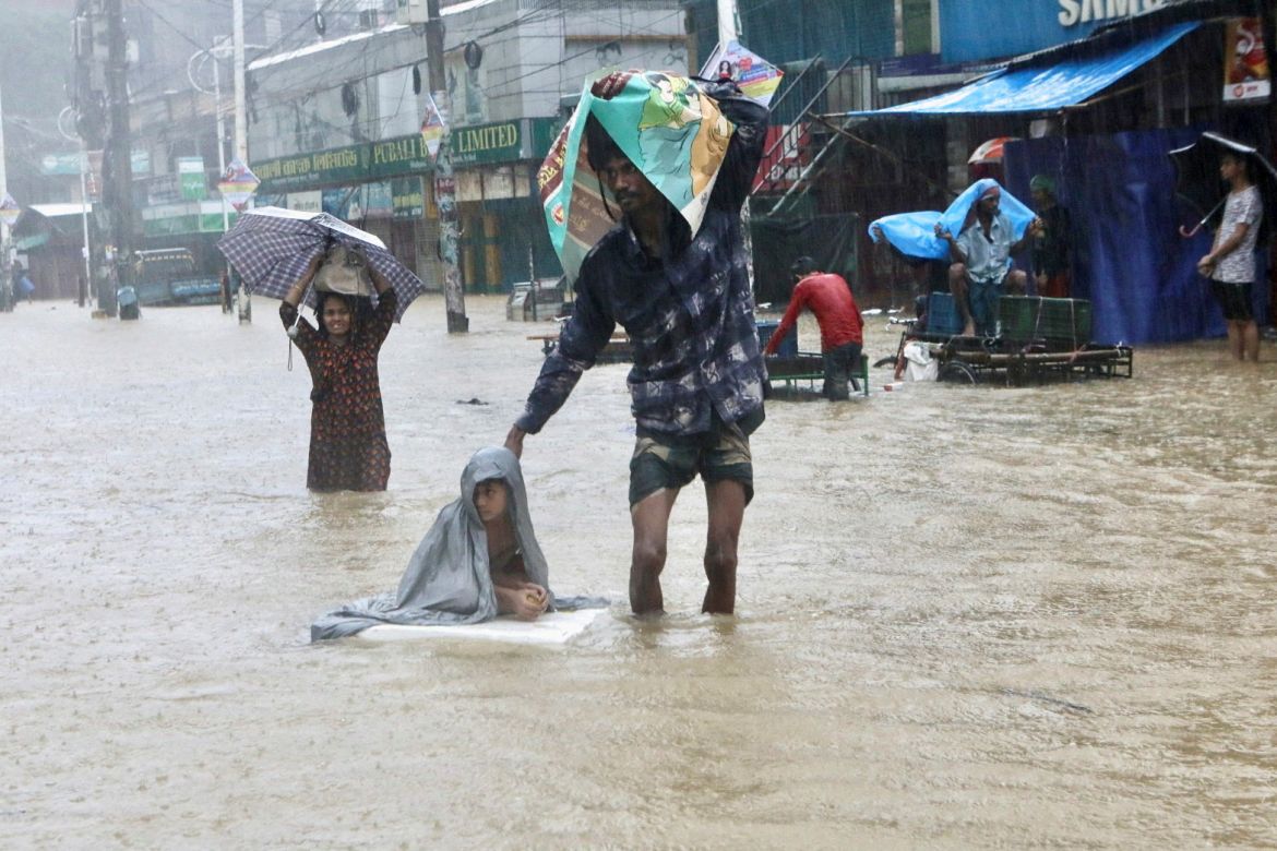 People wade through the water as they look for shelter during a flood