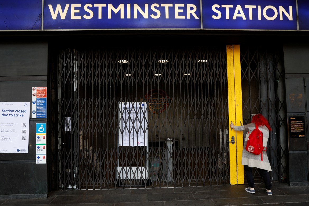 A woman stands outside the closed entrance to the Westminster Undeground Statio