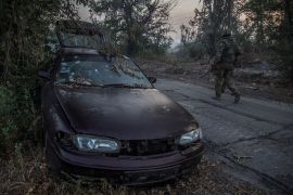 Ukrainian service members walk past a damaged car in the city of Severodonetsk, as Russia's attack on Ukraine continues, Ukraine June 20, 2022