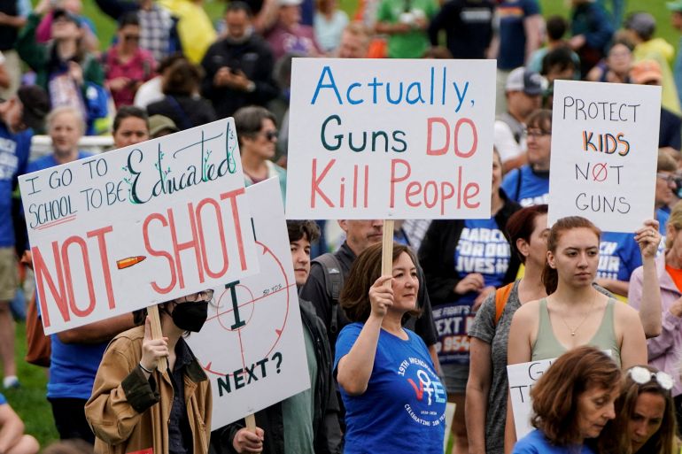 People march in a protest for gun control in the US carrying banners saying "actually guns do kill people' and 'i got to school to be educated, not shot'