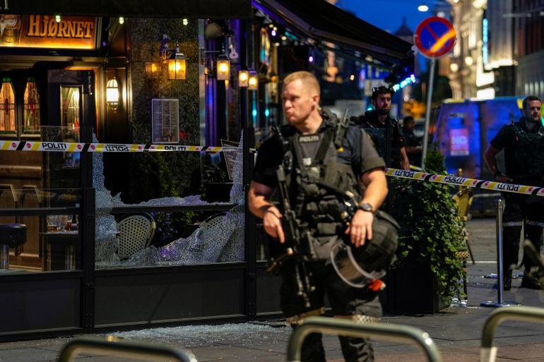 Security forces stand at the site where several people were injured during a shooting outside the London pub in central Oslo.