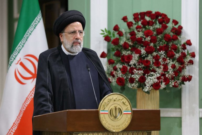 Iranian President Ebrahim Raisi stands at a lectern in front of an Iranian flag