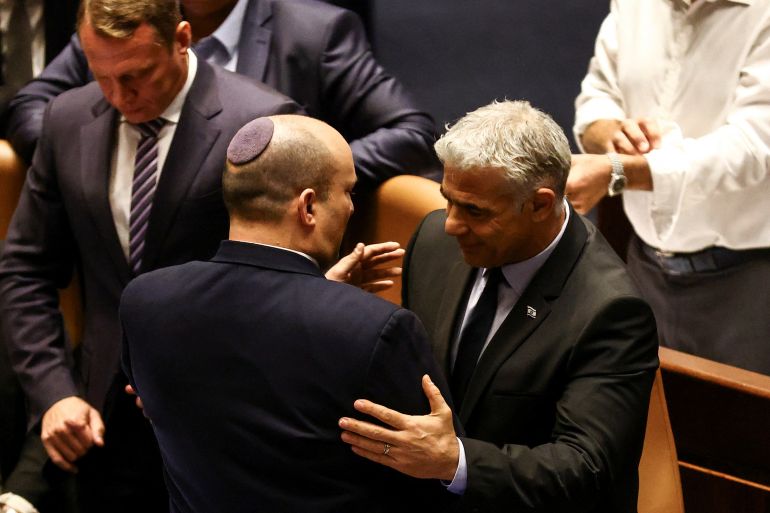 Israeli Prime Minister Naftali Bennett and Foreign Minister Yair Lapid embrace each other