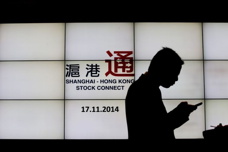Logo Shanghai-Hong Kong Stock Connect di layar dengan pria yang menggunakan ponsel di depan